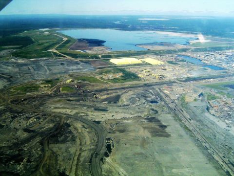 A tar sands mine and plant near Fort McMurray, Alberta, Canada. The recipe is simple: scrape the skin off the earth, boil what you find, wash the residue, dilute it with explosive fluids and send it 3,000 miles to where someone can make an inferior product with it. For some reason, the business model isn’t working. (Wikipedia Photo) 